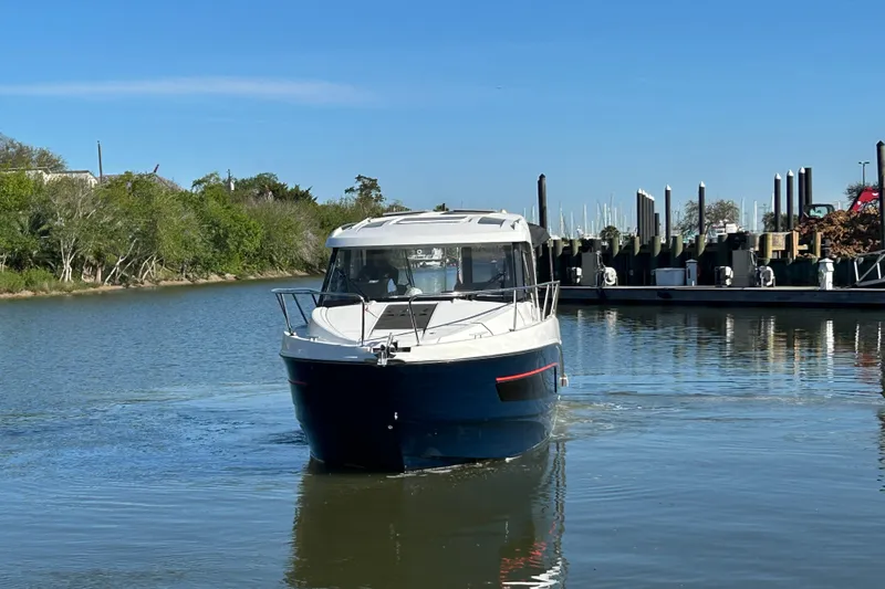Slide: The Image of 2022 Beneteau Antares 9 boat cruising on a calm river near a marina. - 17