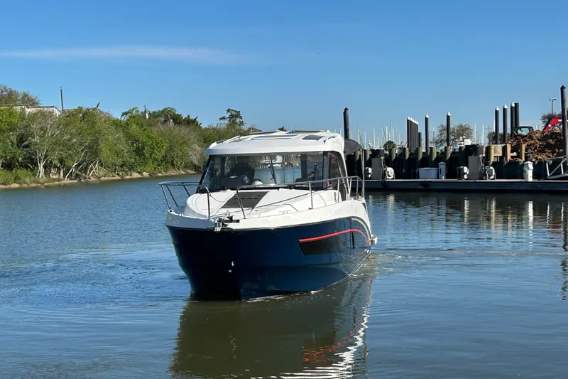 Slide: The Image of 2022 Beneteau Antares 9 boat cruising on a calm river near a marina. - 18