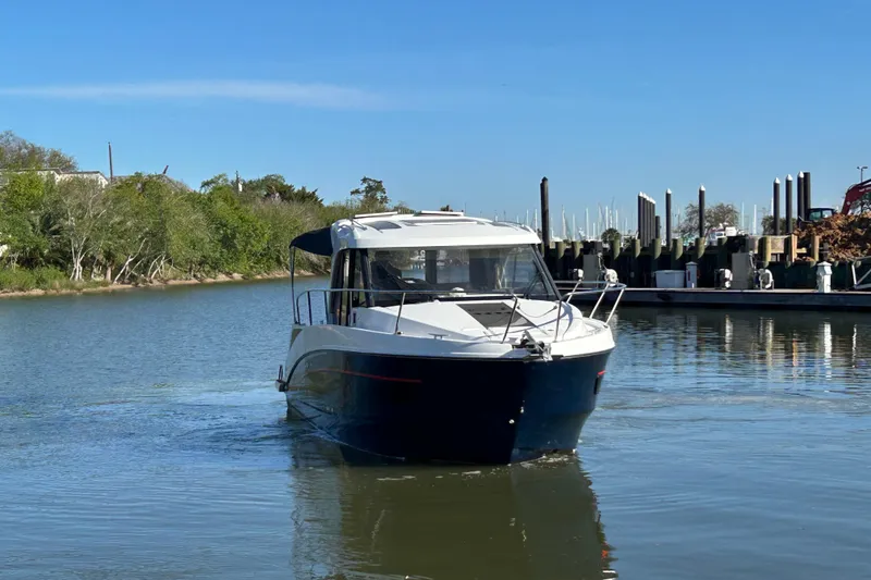 Slide: The Image of 2022 Beneteau Antares 9 cruising on a calm river near a marina. - 21