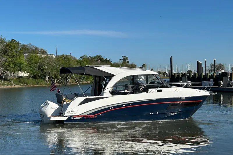 Slide: The Image of 2022 Beneteau Antares 9 boat cruising on a calm river near a marina. - 22