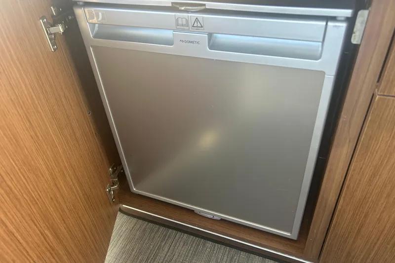 Slide: The Image of Compact Dometic fridge inside 2022 Beneteau Antares 9 boat, wooden cabinetry. - 48