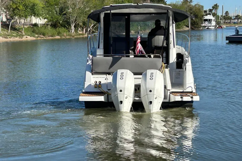 Slide: The Image of 2022 Beneteau Antares 9 boat cruising on a calm river with twin engines. - 9