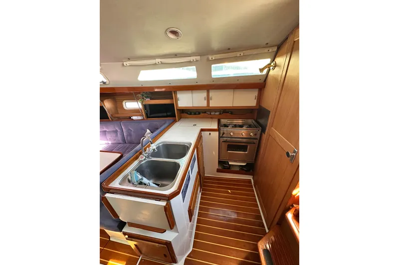 Slide: The Image of Interior of 1994 Catalina 34 MkII sailboat kitchen with sink, stove, and wooden cabinetry. - 10
