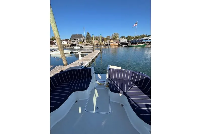 Slide: The Image of 2018 Back Cove 30 boat docked, featuring striped seating and a scenic marina view. - 10