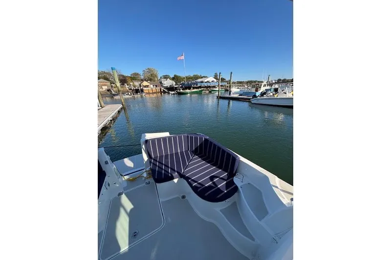 Slide: The Image of 2018 Back Cove 30 boat with striped seating, docked in a serene marina. - 11