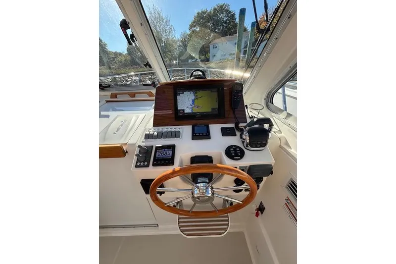 Slide: The Image of 2018 Back Cove 30 boat helm with navigation equipment and wooden steering wheel. - 18