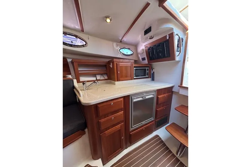 Slide: The Image of 2018 Back Cove 30 yacht interior with kitchenette, featuring wood cabinetry and modern appliances. - 29