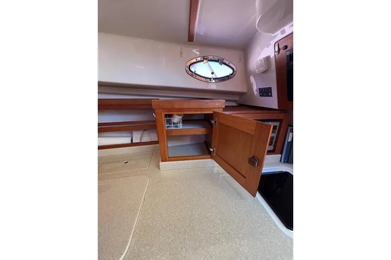 Slide: The Image of Interior of 2018 Back Cove 30 boat with open wooden cabinet and porthole window. - 32