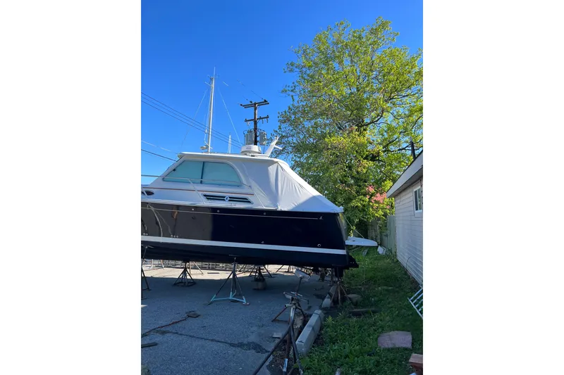 Slide: The Image of 2015 Back Cove 30 boat on stands, surrounded by trees and clear blue sky. - 49