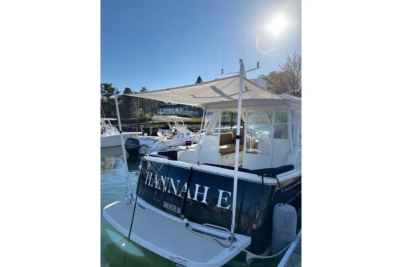 Slide: The Image of 2018 Back Cove 30 boat docked under sunny sky, featuring canopy and seating area. - 5