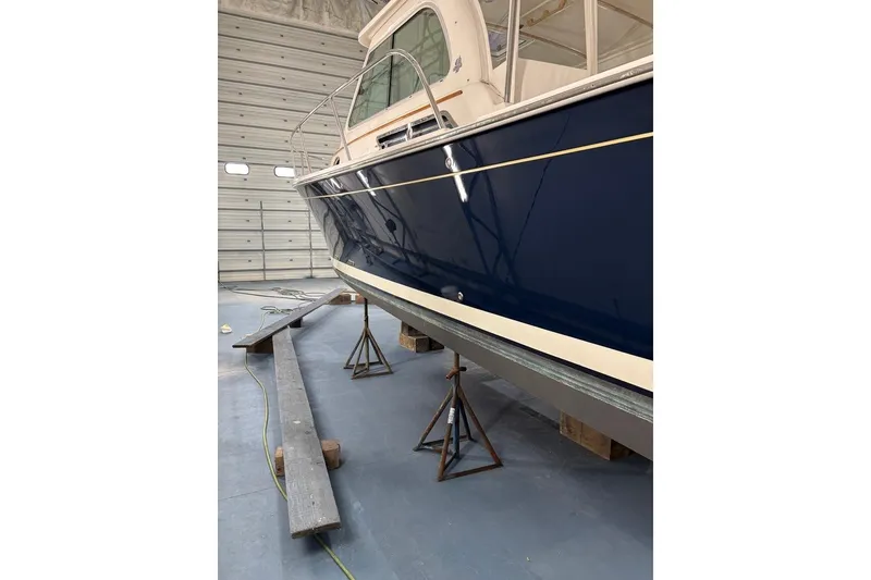 Slide: The Image of 2015 Back Cove 30 boat in storage, blue hull, supported on stands. - 52