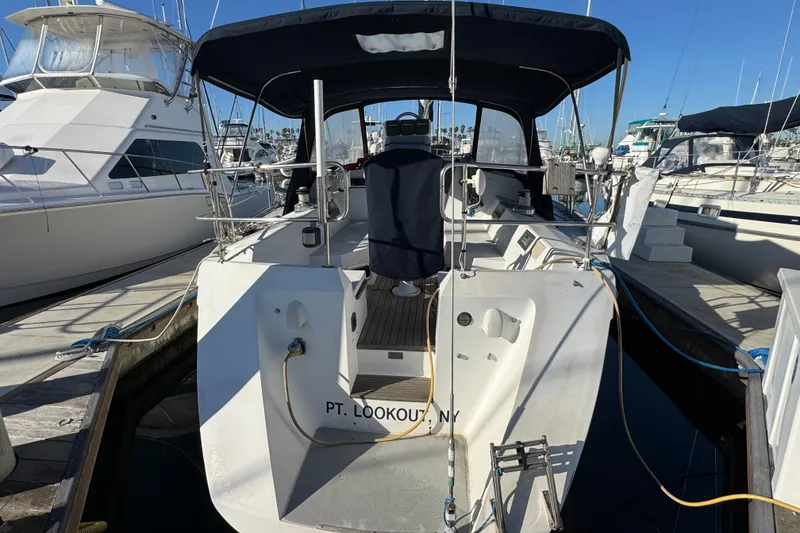 Slide: The Image of 1989 Catalina 42 sailboat docked at marina, featuring covered cockpit and sleek design. - 2