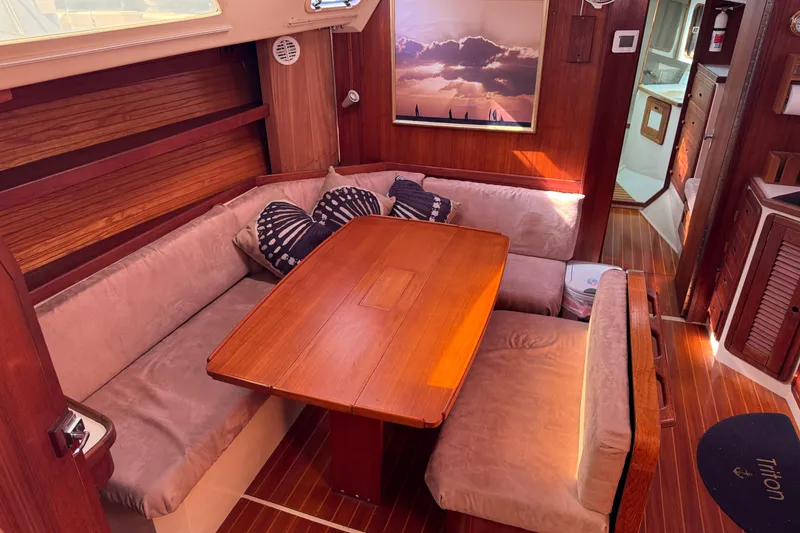 Slide: The Image of Cozy interior of a 1989 Catalina 42 sailboat with wooden dining area and plush seating. - 20