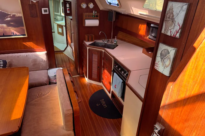 Slide: The Image of Interior of a 1989 Catalina 42 sailboat featuring a cozy kitchen and dining area. - 26