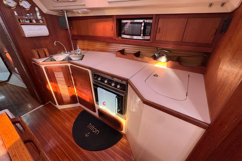 Slide: The Image of 1989 Catalina 42 yacht kitchen with wood cabinetry, stove, sink, and microwave. - 37