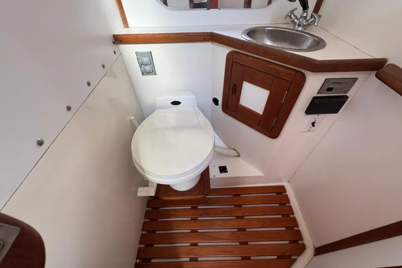Slide: The Image of 1989 Catalina 42 yacht bathroom with toilet, sink, and wooden accents. - 44