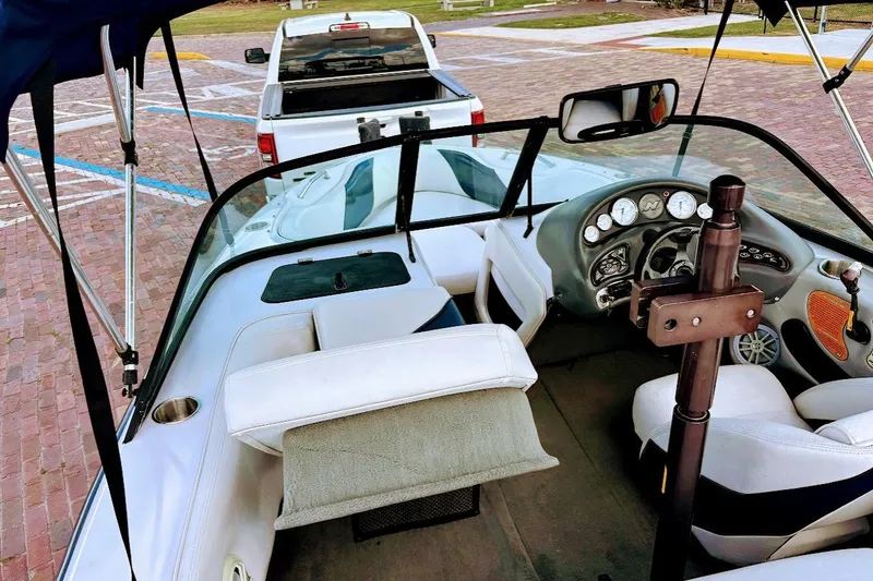 Slide: The Image of 2001 Nautique Air Nautique 210 boat interior with dashboard and seating, parked on brick pavement. - 14
