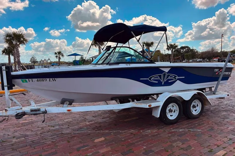 Slide: The Image of 2001 Nautique Air Nautique 210 boat on trailer, parked on brick pavement under a cloudy sky. - 3
