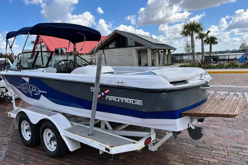 Slide: The Image of 2001 Nautique Air Nautique 210 boat on trailer, parked near waterfront with palm trees. - 4