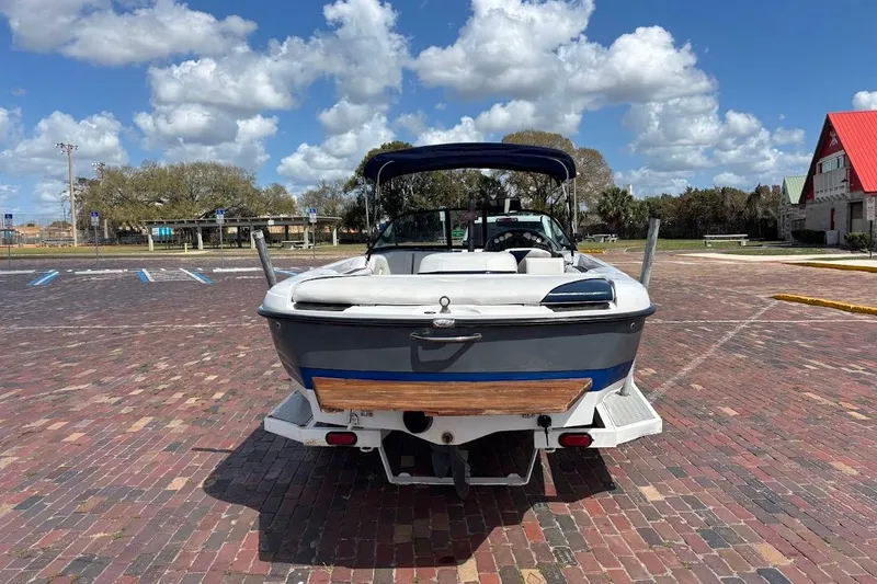 Slide: The Image of 2001 Nautique Air Nautique 210 boat parked on brick pavement under a blue sky. - 5