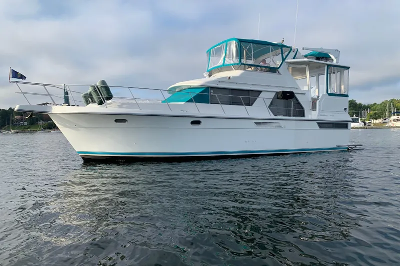 The Image of 1994 Carver 440 Aft Cabin Motor Yacht on calm water, featuring teal accents. - 0