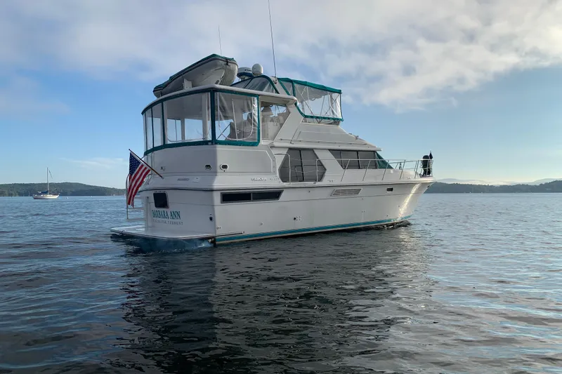 Slide: The Image of 1994 Carver 440 Aft Cabin Motor Yacht on calm water, displaying American flag. - 2
