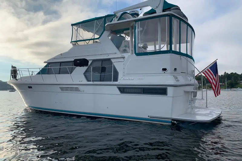 Slide: The Image of 1994 Carver 440 Aft Cabin Motor Yacht on calm water, featuring American flag. - 3