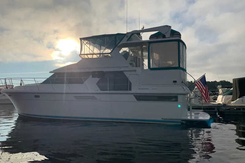 Slide: The Image of 1994 Carver 440 Aft Cabin Motor Yacht docked at sunset with American flag. - 36