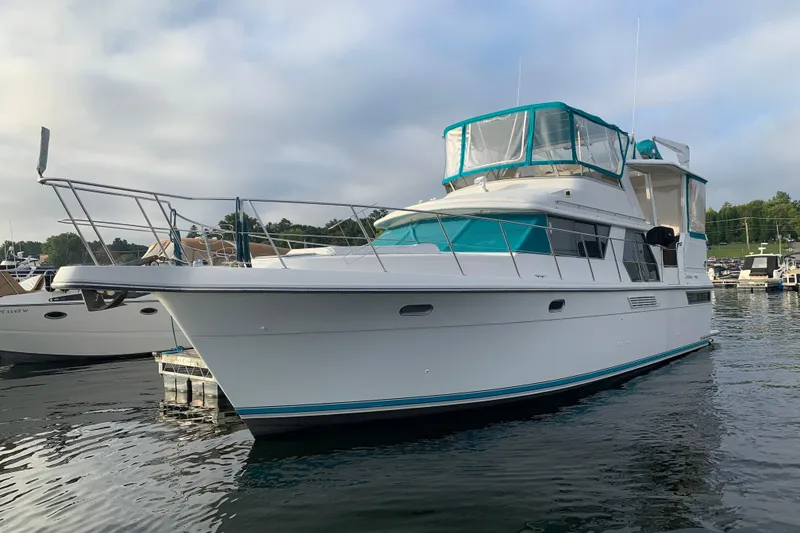 Slide: The Image of 1994 Carver 440 Aft Cabin Motor Yacht docked in a marina, featuring teal accents. - 38