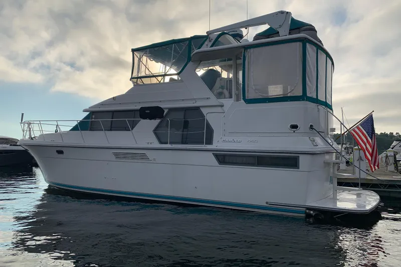 Slide: The Image of 1994 Carver 440 Aft Cabin Motor Yacht docked, featuring sleek design and American flag. - 39