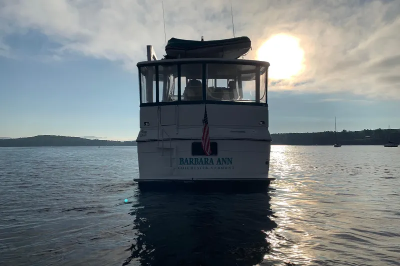 Slide: The Image of Aft view of 1994 Carver 440 Aft Cabin Motor Yacht on serene water at sunset. - 43
