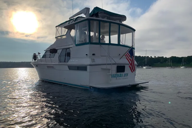 Slide: The Image of 1994 Carver 440 Aft Cabin Motor Yacht on serene water at sunset. - 45