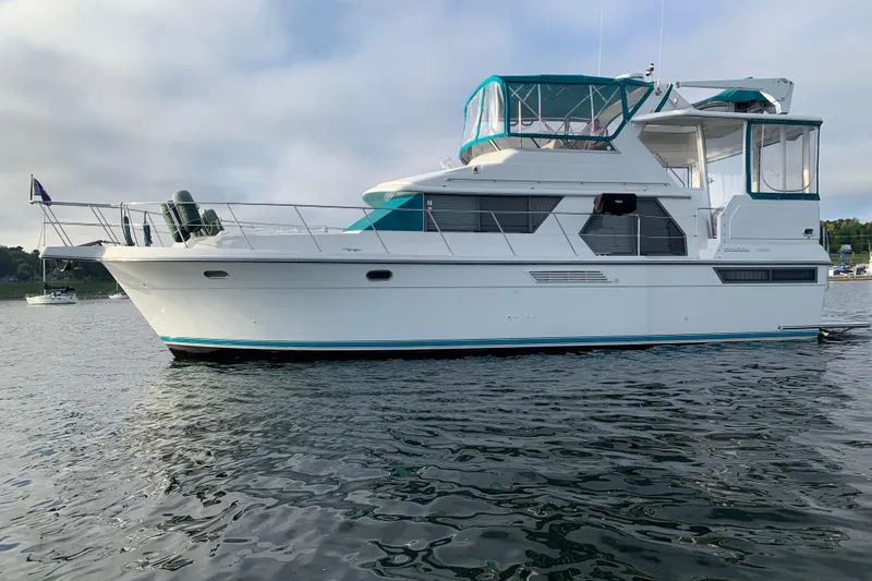 Slide: The Image of 1994 Carver 440 Aft Cabin Motor Yacht on calm water, featuring teal accents. - 47