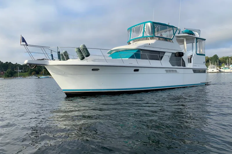 Slide: The Image of 1994 Carver 440 Aft Cabin Motor Yacht on calm water, featuring teal accents. - 48