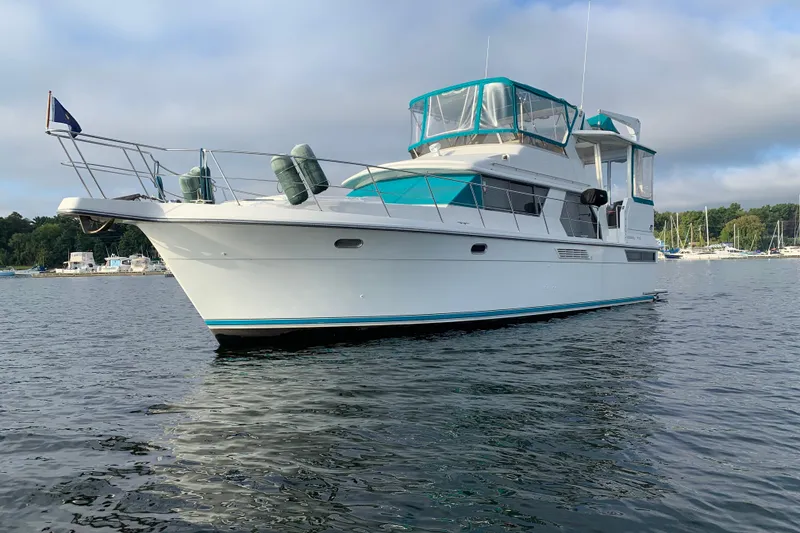 Slide: The Image of 1994 Carver 440 Aft Cabin Motor Yacht on calm water, featuring teal accents. - 49
