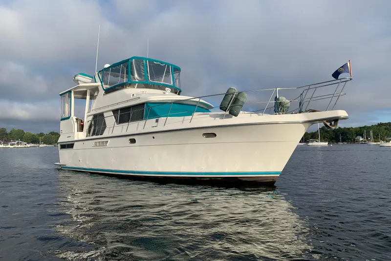 Slide: The Image of 1994 Carver 440 Aft Cabin Motor Yacht on calm water, featuring teal accents. - 52