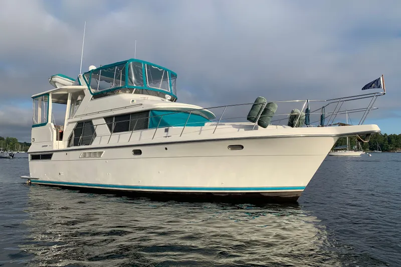 Slide: The Image of 1994 Carver 440 Aft Cabin Motor Yacht on calm water, featuring teal accents. - 53