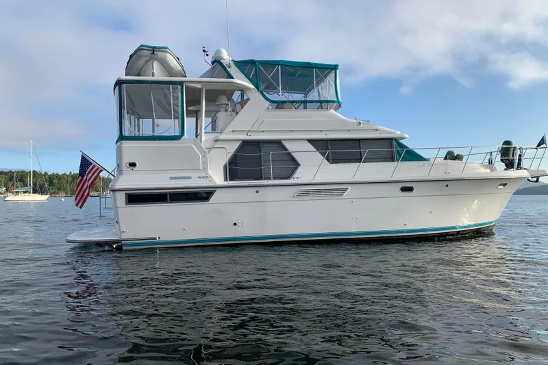 Slide: The Image of 1994 Carver 440 Aft Cabin Motor Yacht on calm water, featuring a sleek design and American flag. - 56