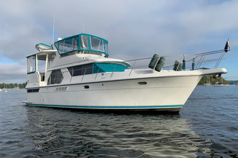 Slide: The Image of 1994 Carver 440 Aft Cabin Motor Yacht on calm water, featuring teal accents. - 57