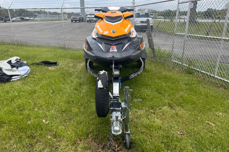 Slide: The Image of 2018 Sea-Doo GTI SE 155 jet ski on trailer, parked on grass near a chain-link fence. - 11