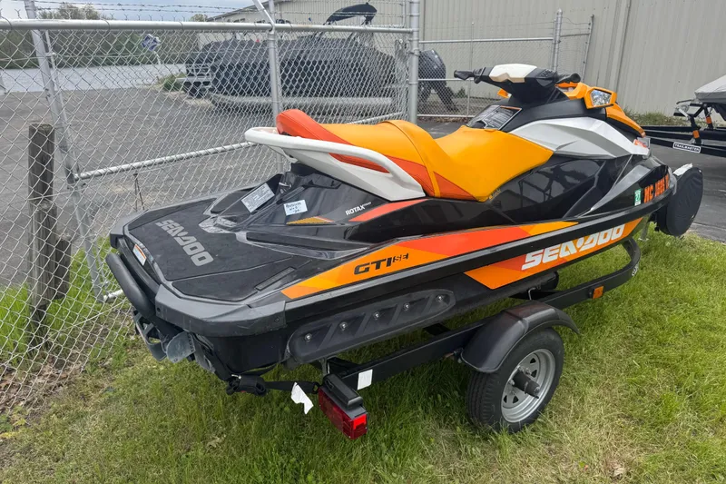 Slide: The Image of 2018 Sea-Doo GTI SE 155 jet ski on trailer, parked near a chain-link fence. - 5