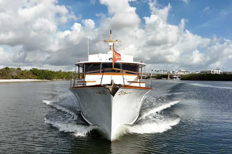 Slide: The Image of 1972 Trumpy 72 Motor Yacht cruising on a scenic waterway under a partly cloudy sky. - 3