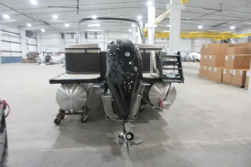 Slide: The Image of 2026 Avalon LSZ Quad Lounge Tri Log pontoon boat in a spacious warehouse setting. - 8