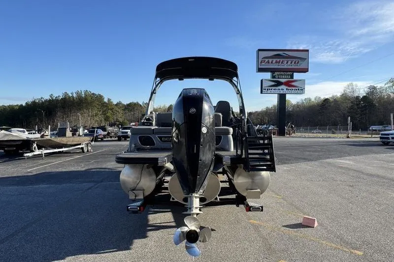 Slide: The Image of 2024 Bennington 25 QXSBA pontoon boat with outboard motor in a parking lot. - 10
