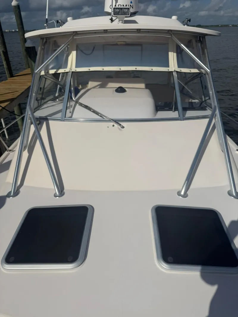 Slide: The Image of 2007 Grady-White Express 330 boat deck with windshield and hatches, docked by the water. - 15