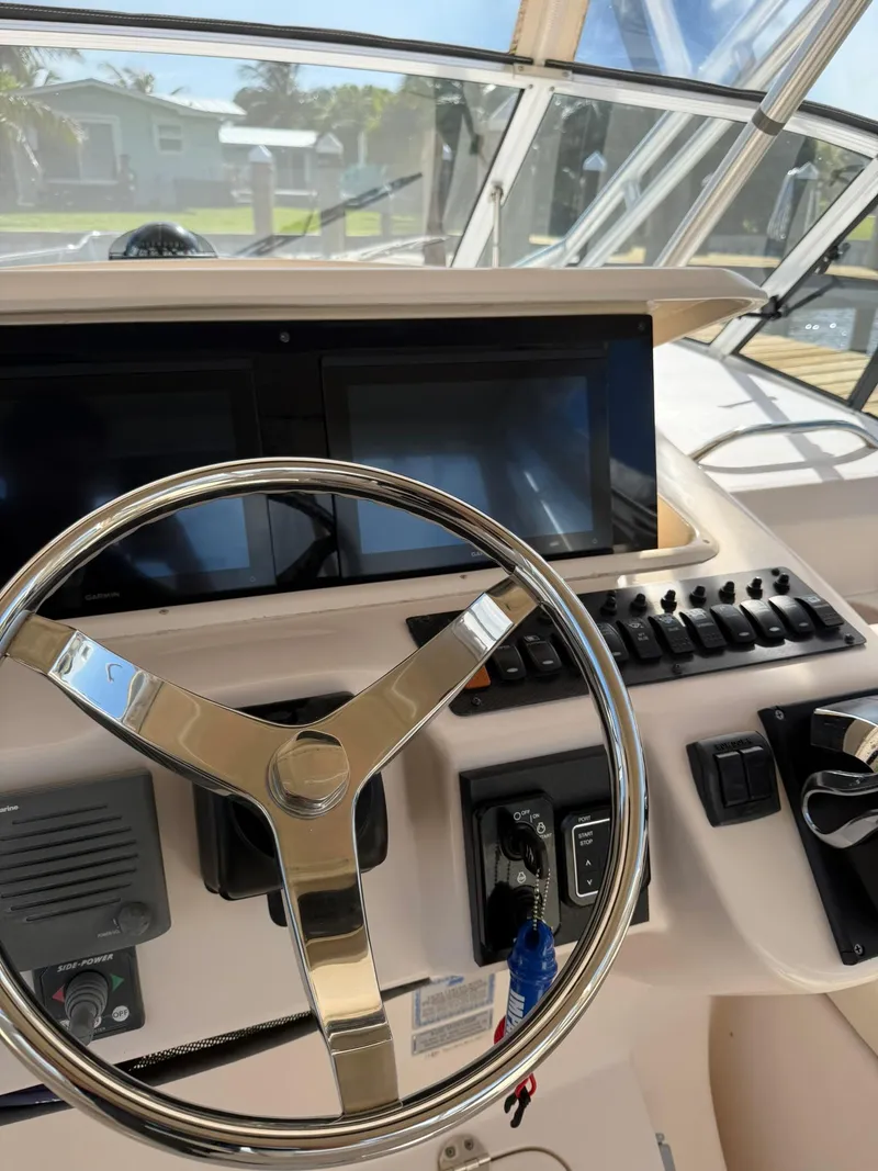 Slide: The Image of Steering wheel and controls of a 2007 Grady-White Express 330 boat cockpit. - 43