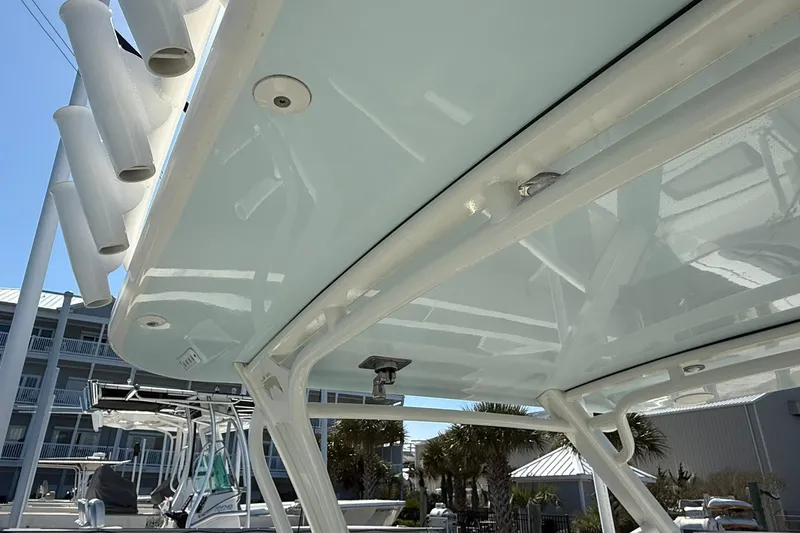 Slide: The Image of 2023 World Cat 280 DC-X boat canopy with rod holders, docked under clear sky. - 12