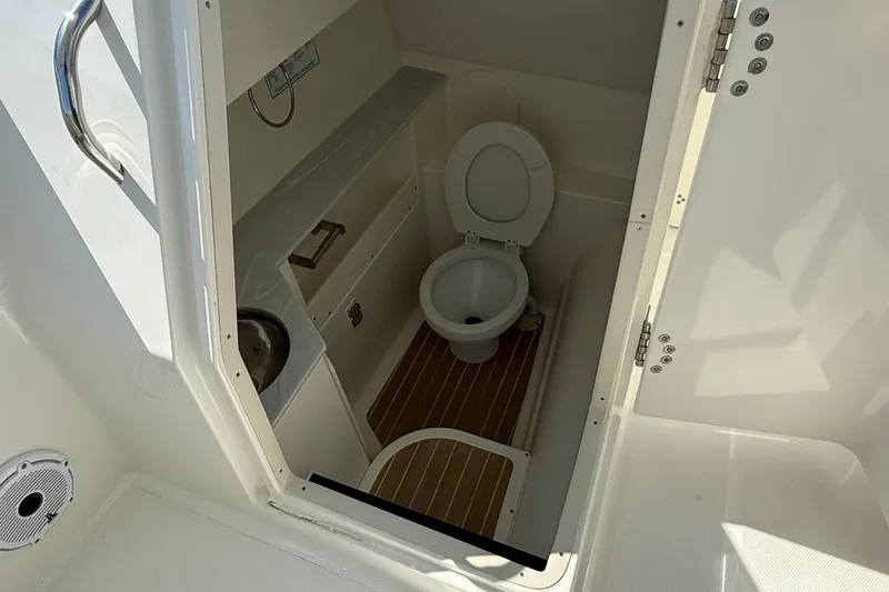 Slide: The Image of 2023 World Cat 280 DC-X boat interior with compact marine toilet and wooden flooring. - 8