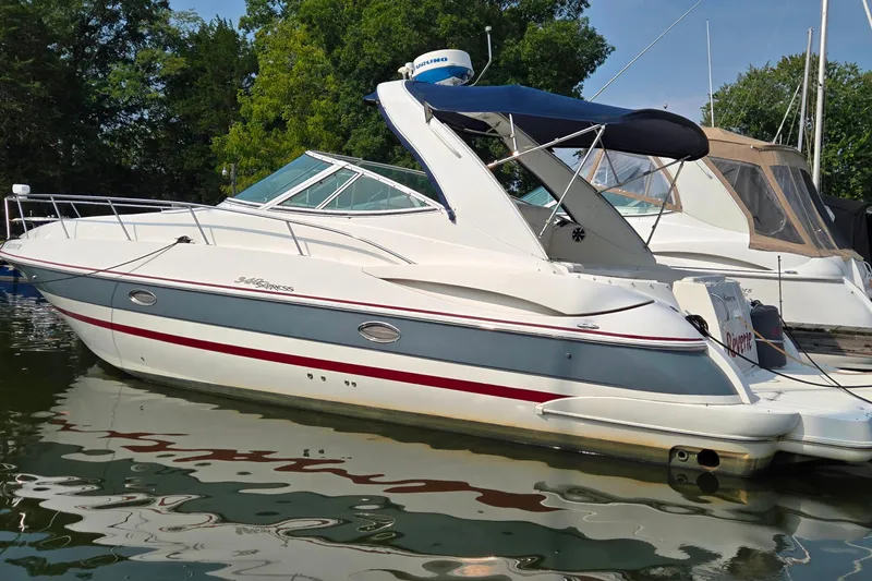 The Image of 2005 Cruisers Yachts 340 Express docked, featuring sleek design and blue canopy. - 0