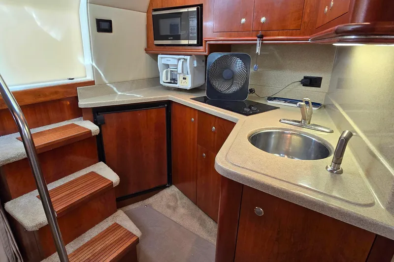 Slide: The Image of 2005 Cruisers Yachts 340 Express galley with sink, microwave, and wooden cabinetry. - 20